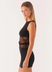 Détail d'une robe noire sans manches avec dentelle florale et nœud papillon à la taille