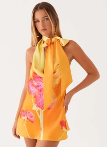Détail du nœud papillon sur l'encolure dos nu d'une robe fleurie en satin orange