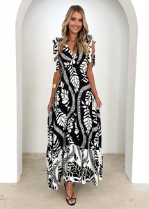 Detail of V-neck printed maxi dress featuring adjustable shoulder bow ties and leaf print