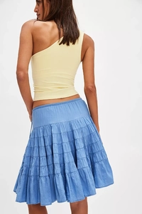 Detail of blue tiered cake skirt and yellow one-shoulder top showing drape and fabric texture