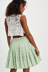 Detail of white crochet vest and light green tiered ruffle skirt with cotton texture