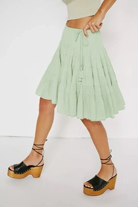 Detail of light green tiered bohemian mini skirt with tassel drawstring and elastic waist