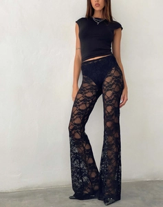 Détail du pantalon évasé en dentelle florale noire transparente à taille haute