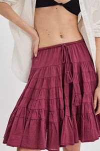 Detail of burgundy tiered skirt featuring elastic waist with braided tassel drawstrings