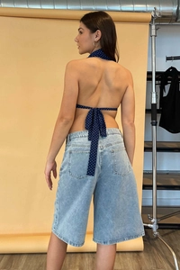 Rückansicht eines gepunkteten Halterneck-Tops mit Bindebändern und Denim-Shorts