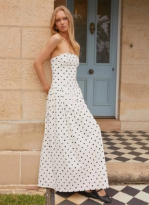 Detail of bohemian strapless maxi dress featuring classic black polka dots on white fabric