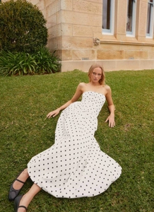 Fashionable strapless white maxi dress with black polka dots on lush green grass