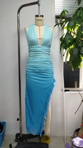 Detail of light blue halter dress featuring ruched chiffon fabric and high slit ruffle hem