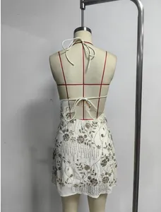 Détail du laçage croisé d'une mini-robe blanche à paillettes avec broderie dorée