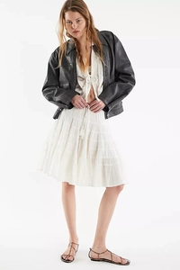 Detailed look at tiered white skirt paired with a black leather jacket and lace top