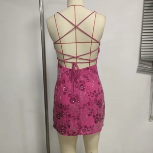 Detail of fuchsia sequin dress featuring back cross-strap design and floral embroidery