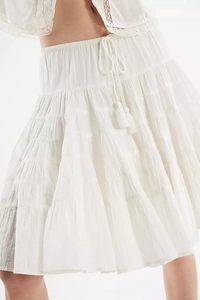 Detail of white tiered skirt with elastic smocked waist and boho tassel drawstrings