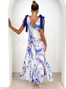 Back view of a white V-neck floral maxi dress with blue shoulder ribbons and ruffles