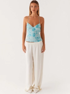 Haut licou bleu clair avec broderies florales et paillettes et pantalon blanc