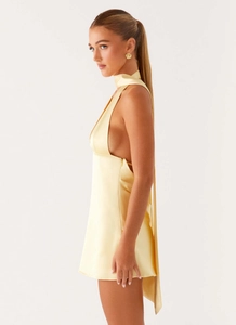 Detailed side view of light yellow satin mini dress with halter neck and backless cut