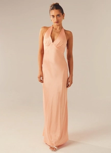 Detail of peach satin halter neck maxi dress with deep V-neckline and elegant pleated bust