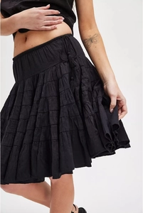 Close-up of black tiered mini skirt featuring layered ruffles and tassel drawstring details