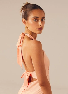 Detail of peach pink backless dress showing elegant oversized bow tie and satin fabric