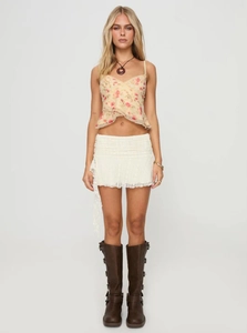Detail of floral mesh camisole with asymmetric ruffle hem and lace mini skirt