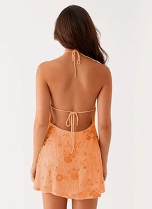 Détail d'une mini-robe dos nu à paillettes avec broderies florales oranges et dos ouvert