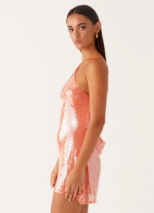 Detailed view of shimmering orange sequin cocktail dress with thin straps and draped neckline