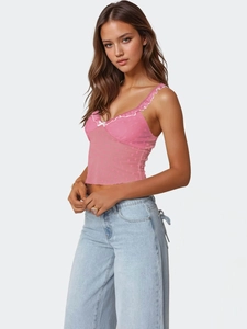 Détail du haut en maille rose avec motif de petits cœurs et nœud blanc décoratif