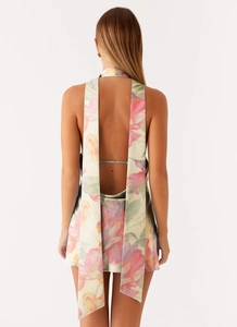 Macro detail of the backless satin dress showing the floral pattern and draped halter ties