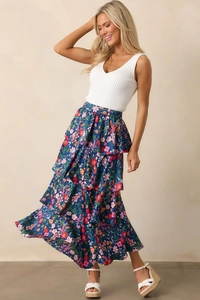 Detail of navy floral tiered maxi skirt paired with a white ribbed V-neck knit vest