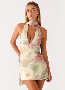Detailed close-up of halter neck floral mini dress with pink blossoms on beige fabric