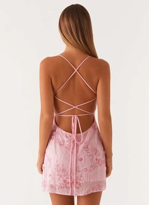 Detail of pink dress featuring intricate sequin embroidery and cross-back tie design