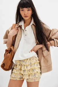Detail of layered floral chiffon ruffle skirt paired with a khaki utility jacket and bag