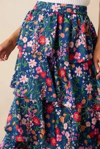 Detailed view of the tiered ruffles and colorful floral print on the navy blue maxi skirt