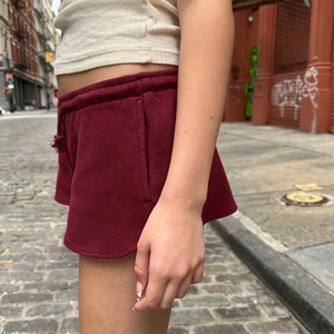 Detailansicht der weinroten Shorts mit Waffelstruktur und abgerundetem Saumdesign