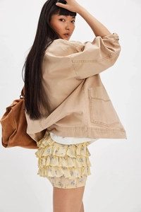 Detailed look at layered floral ruffle skirt and khaki utility jacket with metal buttons