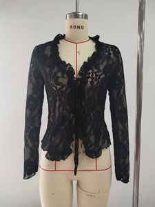 Detail of black floral lace fabric with ruffled edges and tie-front closure on a cardigan