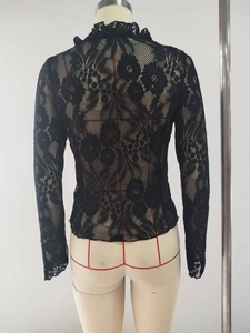 Detail view of black sheer lace top featuring large floral patterns and ruffled collar