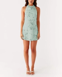 Détail d'une mini robe vert menthe à paillettes avec broderie florale et dos nu