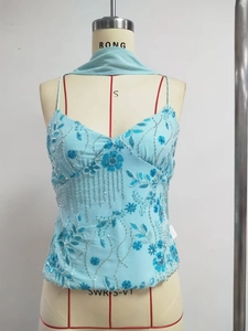Detail of light blue sequin tank top with floral embroidery and beaded tassel fringe