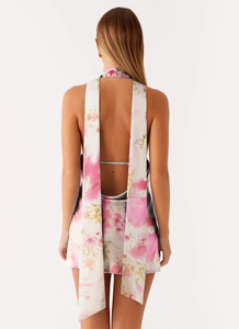 Detail of floral backless mini dress featuring long flowing halter neck ties and satin finish