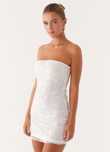 Close-up of white strapless lace dress with delicate floral embroidery and sequins