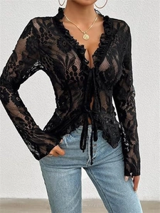 Detail of floral lace texture on a black tie-front crop top with ruffled V-neckline