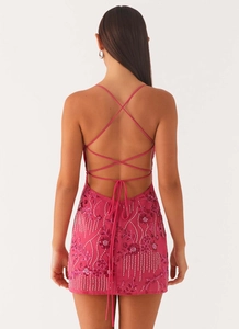 Close-up of hot pink sequin dress featuring criss-cross back straps and bead embroidery