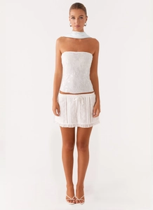 Detail of white two-piece set featuring floral embroidery and ruffled hem skirt