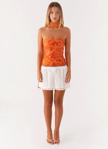 Close-up of orange tube top featuring delicate floral embroidery and matching scarf detail
