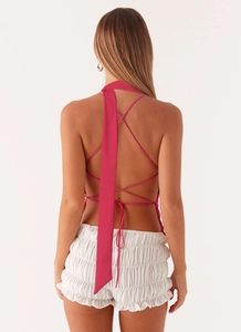 Detail of cross-straps and open back design on a pink sequin halter top