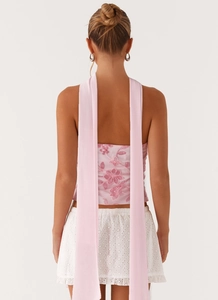 Detail of pink floral sequin tube top featuring long ribbons and eyelet skirt