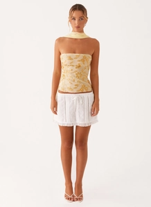 Detail of sequin floral embroidery on cream tube top and white eyelet skirt with scarf