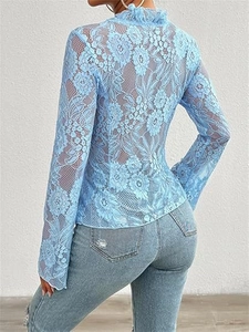 Detail of light blue floral lace fabric and elegant ruffle trim on the long sleeve top