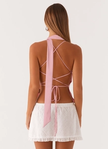 Detail view of pink halter backless top with crossover straps and eyelet skirt