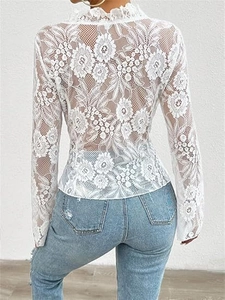 Detail of white lace tie-front top featuring floral sheer mesh and elegant ruffled back